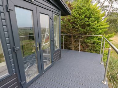 A deck with glass doors and railing at John's Folly
