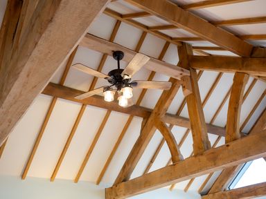 A ceiling fan with light bulbs and wooden beams at Nature's Lodge in Cookley