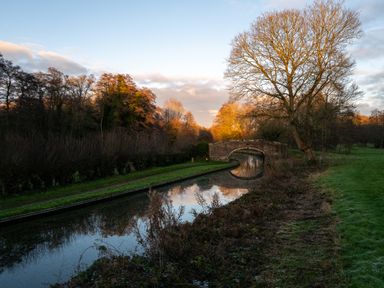 A canal with a bridge and trees at Nature's Lodge in Cookley
