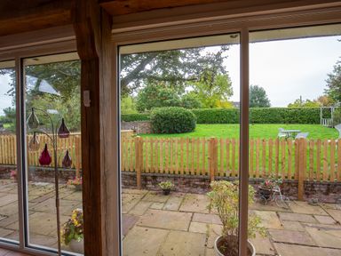 A view of a garden with a table and chairs from inside Nature's Lodge in Cookley