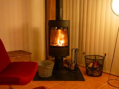 A living room with a fireplace and a chair at Nature's Lodge Cookley