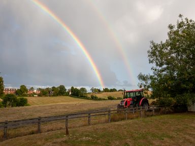 A tractor near a fence under a rainbow at Nature's Lodge in Cookley