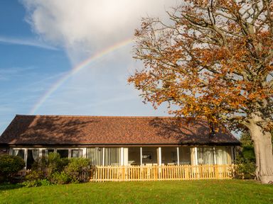 A house with a fence and tree under a rainbow at Nature's Lodge in Cookley