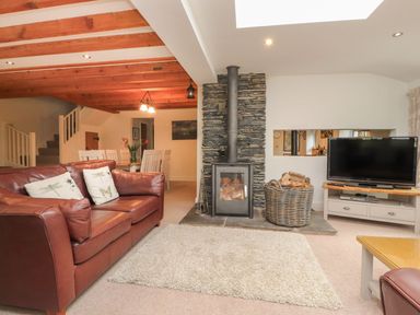 A living room with a fireplace and television at Bobbin Mill Cottage in Ulverston