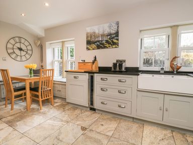 A kitchen with a dining table and wooden chairs at Bobbin Mill Cottage in Ulverston