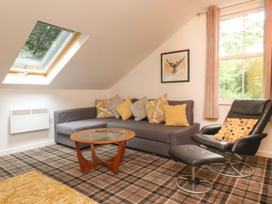 A living room with a sofa, table, and armchair at Bobbin Mill Cottage in Ulverston