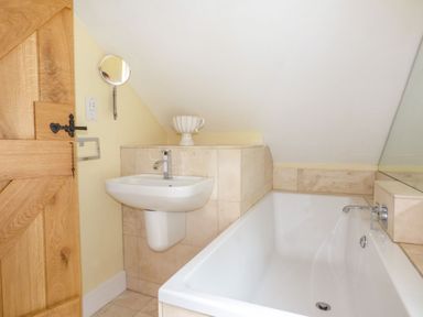 A bathroom with a bathtub and wash basin at Bobbin Mill Cottage, Ulverston