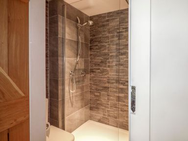 A shower area with tiled walls at Bobbin Mill Cottage in Ulverston