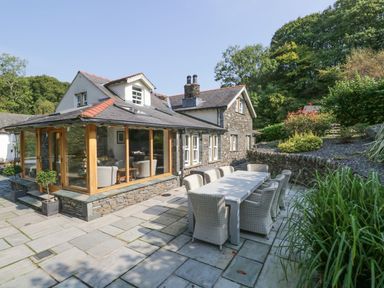 An outdoor area with a stone patio and a dining table at Bobbin Mill Cottage Ulverston