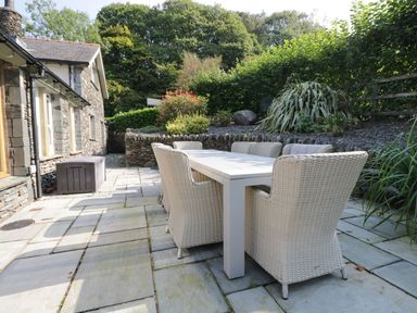 A garden with a patio set and plants at Bobbin Mill Cottage in Ulverston