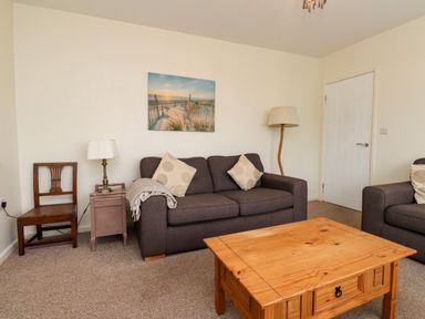A living room with a sofa, coffee table and lamp at Gelli - Morfa Nefyn