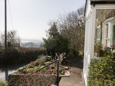 A garden with flowering plants and bushes beside a white building with windows at Gordons View Pleasant Stile near Gloucester