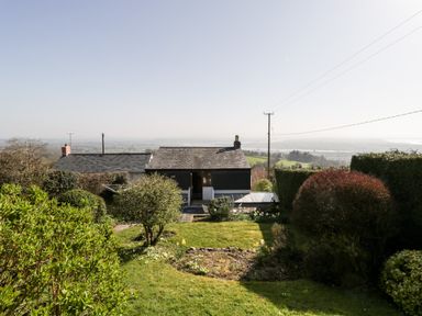 A garden with shrubs and a lawn overlooking houses and distant fields at Gordons View in Pleasant Stile near Gloucester