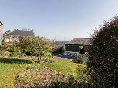 A garden with grass, bushes, flowers, and buildings in the background at Gordons View Pleasant Stile near Gloucester