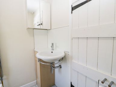 A small bathroom with a round sink cabinet mirror and a wooden door at Gordons View Pleasant Stile near Gloucester