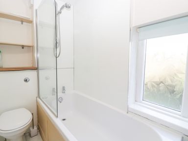 A bathroom with a bathtub shower toilet and frosted window at Gordons View Pleasant Stile near Gloucester