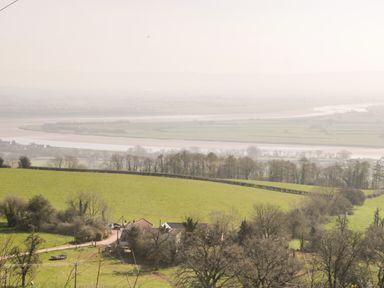 A rural landscape with green fields trees a dirt road and a house near a river at Gordons View in Pleasant Stile near Gloucester