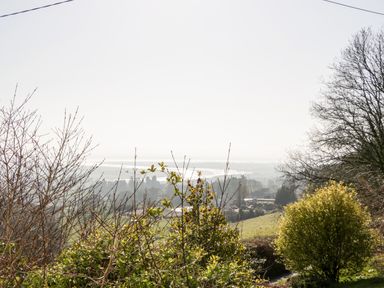A landscape view with bushes and trees overlooking fields and water at Gordons View Pleasant Stile near Gloucester