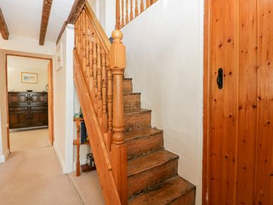 A wooden staircase with a railing in a hallway leading to a room with a dark wooden cabinet at Gordons View Pleasant Stile near Gloucester