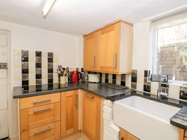 A kitchen corner with wooden cabinets a black countertop a white sink and checkerboard tiled backsplash at Gordons View Pleasant Stile near Gloucester