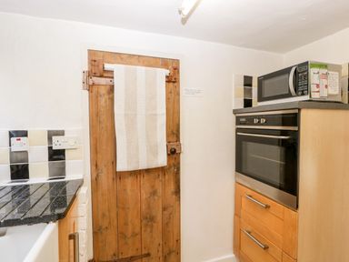 A kitchen corner with a wooden door with a towel hanging on it an oven with drawers below and a microwave on top at Gordons View Pleasant Stile near Gloucester