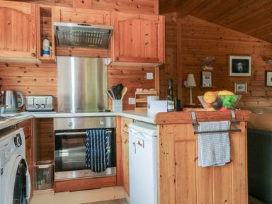 A kitchen with wooden cabinets and appliances at Watendlath in Keswick