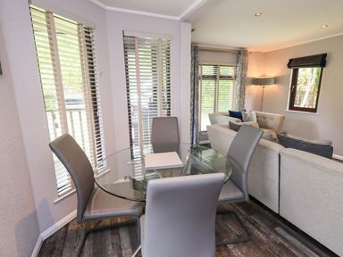 A dining room with a glass table and chairs at Costapacket, Grasmere 12, White Cross Bay near Windermere