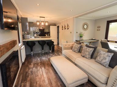 A living room with a sofa and bar stools at Costapacket Grasmere 12, White Cross Bay near Windermere