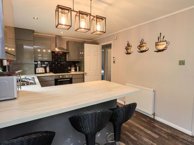 A kitchen with a countertop and bar stools at Costapacket, Grasmere 12, White Cross Bay near Windermere