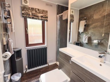 A bathroom with a sink, toilet, and window at Costapacket, Grasmere 12, White Cross Bay near Windermere