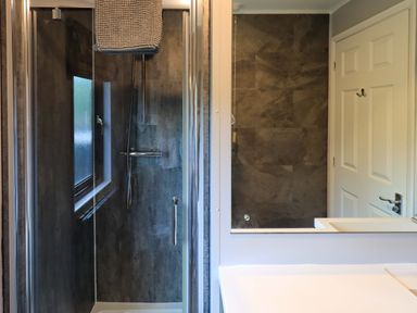 A bathroom with a shower, towel, mirror, and door at Costapacket in Grasmere 12, White Cross Bay near Windermere