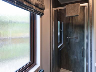 A bathroom with a shower and window at Costapacket, Grasmere 12, White Cross Bay near Windermere
