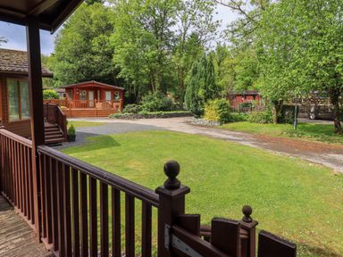 An outdoor area with wooden cabins and greenery at Costapacket Grasmere 12, White Cross Bay near Windermere