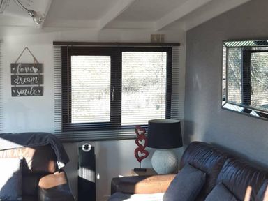 a living room with a window, a lamp, and a decorative sign at Hafan y Mor Haven - Holiday Accommodation 10104 in Pwllheli