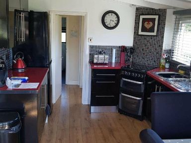 a kitchen with black cabinets and red countertops at Hafan y Mor Haven - Holiday Accommodation 10104 in Pwllheli
