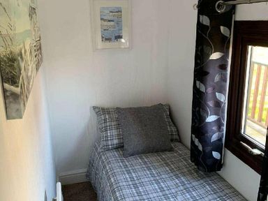 a small bedroom with a single bed and a framed picture on the wall at Hafan y Mor Haven - Holiday Accommodation 10104, Pwllheli