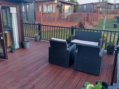 a deck with two chairs and potted plants at Hafan y Mor Haven - Holiday Accommodation 10104 Pwllheli