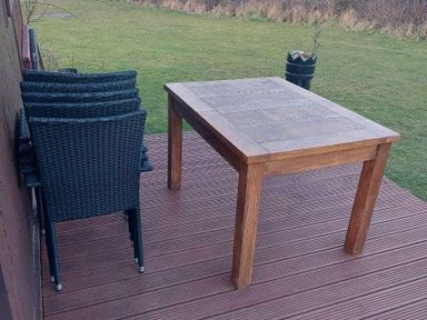 a wooden table and stacked chairs on a deck overlooking a grassy area at Hafan y Mor Haven - Holiday Accommodation 10104 Pwllheli