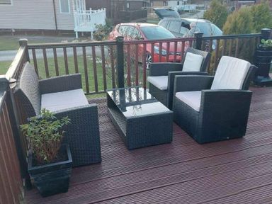 a seating area with two chairs and a table on a deck at Hafan y Mor Haven - Holiday Accommodation 10104, Pwllheli