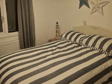 A bedroom with a striped bed and lighthouse decor at Hafan y Mor Haven - Holiday Accommodation 10104, Pwllheli