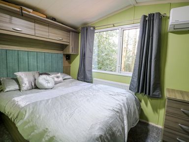 A bedroom with a bed and window at Wild Duck Holiday Park in Belton, Norfolk