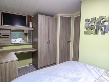 A bedroom with a bed, wardrobe, and television at Wild Duck Holiday Park in Belton, Norfolk
