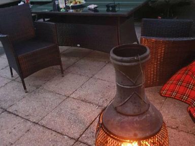 a seating area with two chairs and a chiminea on a patio at Hafan y Mor Haven - Holiday Accommodation 11370 in Pwllheli