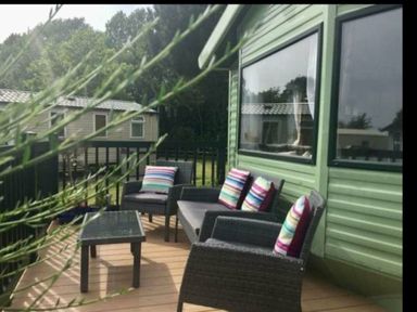 a seating area with colorful cushions and a table on a deck at Hafan y Mor Haven - Holiday Accommodation 11370 Pwllheli