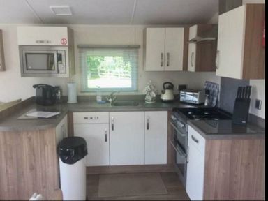 a kitchen with cabinets, a sink, an oven and a microwave at Hafan y Mor Haven - Holiday Accommodation 11370 in Pwllheli