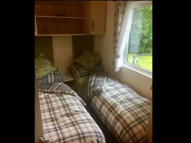 a room with two single beds covered in plaid bedding at Hafan y Mor Haven - Holiday Accommodation 11370 in Pwllheli