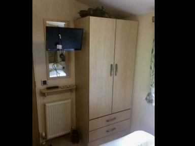 a wooden wardrobe with a mirror and TV mounted above at Hafan y Mor Haven - Holiday Accommodation 11370, Pwllheli