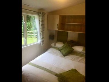 a bedroom with a double bed and a window with curtains at Hafan y Mor Haven - Holiday Accommodation 11370 Pwllheli