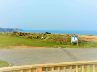a view of the ocean and a grassy area with signs at Perran Sands - Holiday Accommodation 12174 in Perranporth