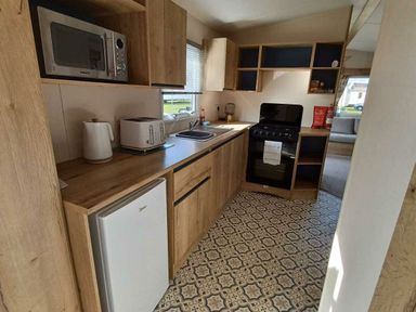 a kitchen with a microwave, toaster, sink, and stove at Hafan y Mor Haven - Holiday Accommodation 12637, Pwllheli